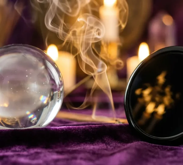 Una sfera di cristallo trasparente e uno specchio nero riflettente disposti simmetricamente su superficie scura per la divinazione